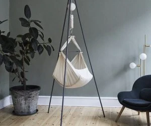 Lækker babygyngestol på en stilfuld indretning med plante og lænestol. Perfekt til tryghed og hygge for din baby.