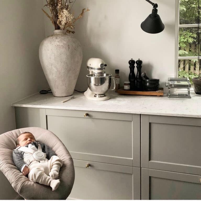 Børnevenligt køkken med sovende baby i autostol, moderne børnevenlig design, sikker babystol.
