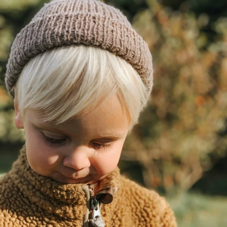 Blond dreng i warmt sweater og hue, udendørs, efterår, barneglæde, børnevenligt.