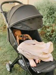 Senior sleepende baby i en buggy med tæppe, udendørs, trygt og komfortabelt.