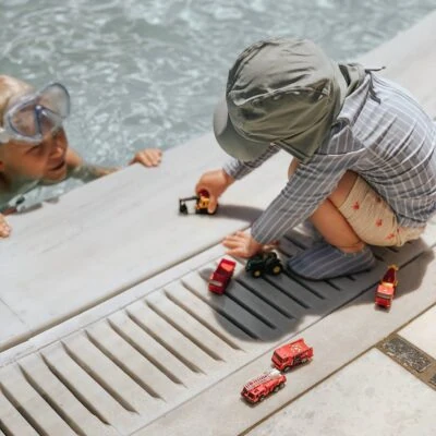 Børn leger ved vandkanten med legetøjsbåde og krykker.