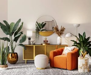Grønne planter i gulddetaljer i stuen, moderne indretning med orange sofa og dekorative elementer.