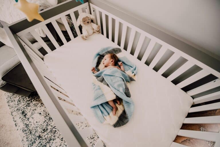 Blødt babylegesel med baby, der ligger på seng.