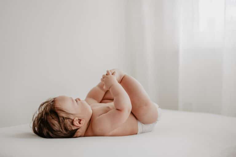 Børne baby der leger på sengen, afslappet og glad.