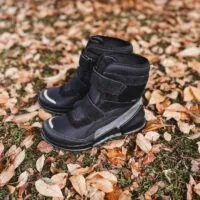 Sort vinterstøvler til børn på jord med efterårsløv, perfekt til forbedret skole- og udendørsbrug.