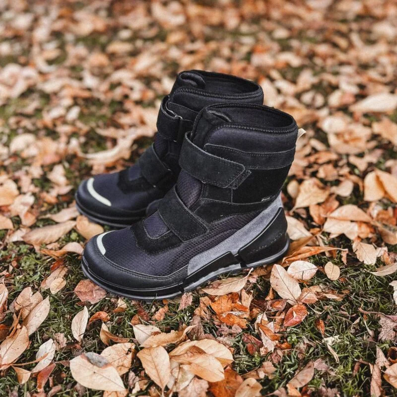Sort vinterstøvler til børn på jord med efterårsløv, perfekt til forbedret skole- og udendørsbrug.