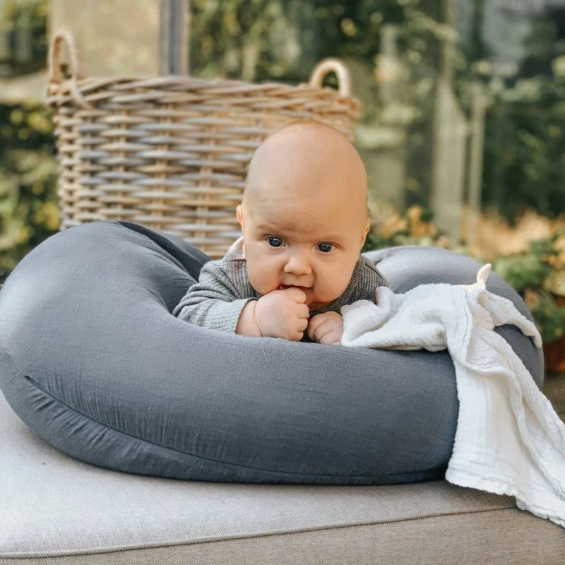 Blødt babynet i gråt, baby ligger på blegebams, udendørs, trygt og hyggeligt.