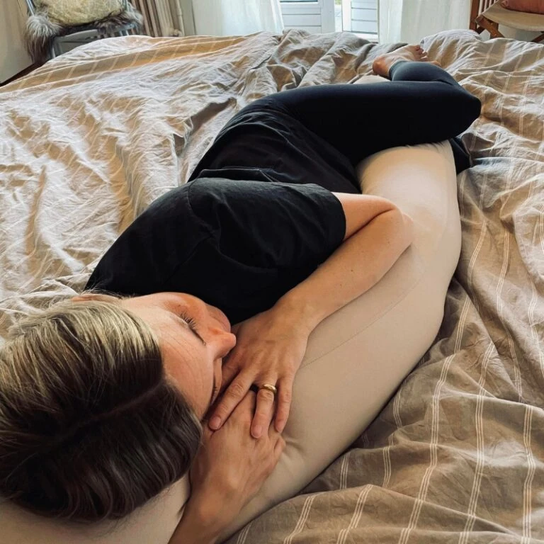 Beroligende graviditetskarp med kvinde, der hviler komfortabel på sengen.